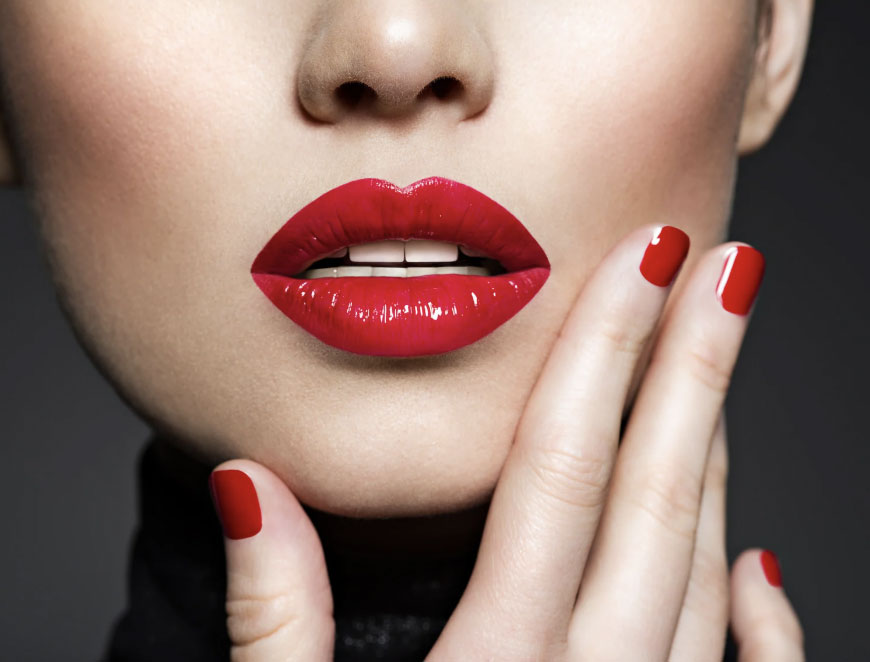 Closeup of a woman's face with red lipstick and red nail polish